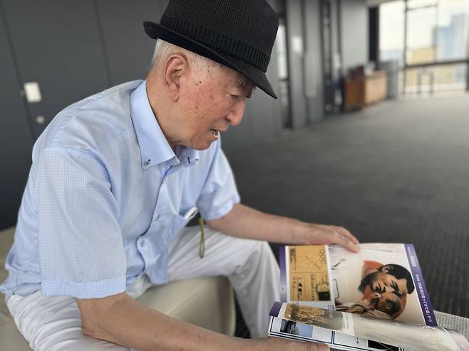 Son Jeong-in, the eldest son of marathoner Son Kee-chung, looks through materials from a symposium held at Meiji University in honor of the 100th anniversary of his father's birth. [KIM HYUN-YE]