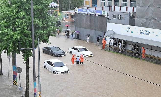 7월17일&nbsp; 광주 북구 중흥동 북구청 사거리에서 전남대 방향으로 향하는 일반도로에는 사람 종아리 높이까지 물이 차올랐다. 119 대원들이 차량 운전자를 구조하고 있다. ⓒ무등일보