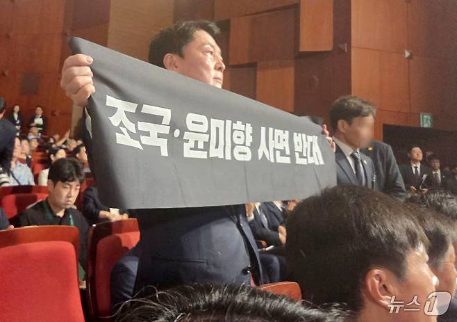 안철수 국민의힘 당대표 후보가 15일 오전 서울 종로구 세종문화회관에서 열린 제80주년 광복절 경축식에 참석해 경축사 중인 이재명 대통령을 향해 조국 전 조국혁신당 대표와 윤미향 전 의원의 사면 반대 플래카드를 들어보이며 항의하고 있다. (안철수 캠프 제공) 2025.8.15/뉴스1