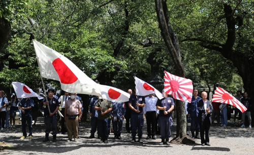 15일 도쿄 야스쿠니신사를 방문한 사람들이 욱일기와 일장기를 들고 있다.(사진=연합뉴스)