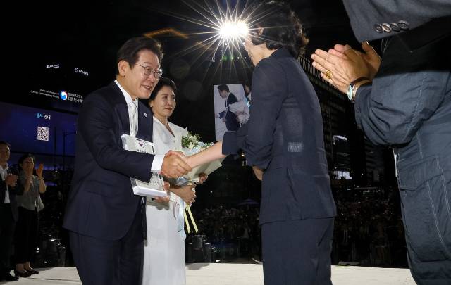 이재명 대통령과 김혜경 여사가 15일 서울 세종대로 광화문광장에서 열린 제21대 대통령 국민임명식 '광복 80년, 국민주권으로 미래를 세우다' 행사에서 국민대표인 이연수 NC AI 대표, 이국종 국군대전병원장으로부터 '빛의 임명장'과 꽃다발을 받고 있다. 연합뉴스