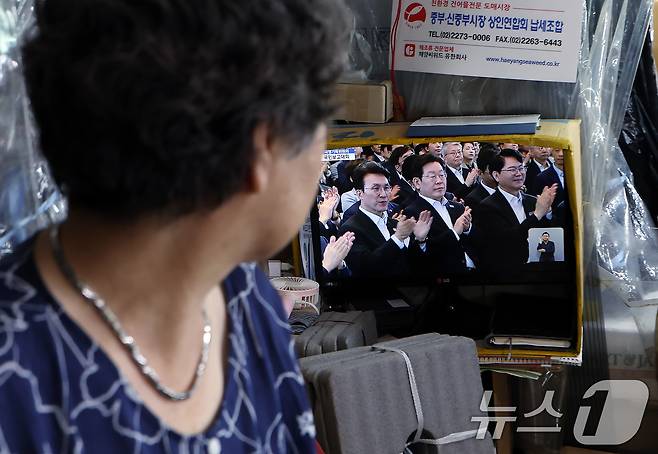 13일 오후 서울 도심의 한 전통시장에서 상인이 국정기획위원회 국민보고대회 '국민이 주인인 나라 함께 행복한 대한민국’ 생중계를 지켜보고 있다. 2025.8.13/뉴스1 ⓒ News1 박정호 기자