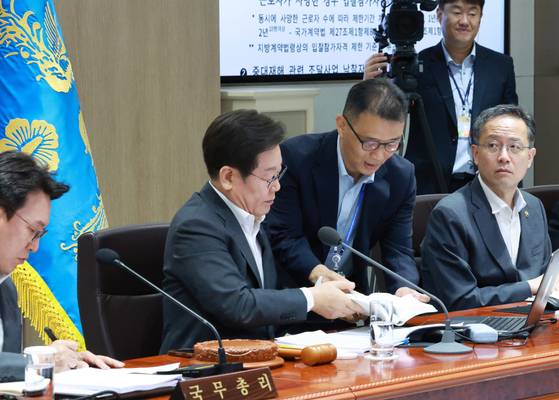이재명 대통령이 29일 서울 용산 대통령실 청사에서 열린 국무회의에서 국무위원들과 중대재해 근절대책 토론을 하며 대통령실 참모진으로부터 관련 법령 자료를 받고 있다. 연합뉴스