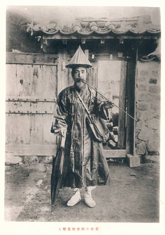 입에는 장죽을 물고 한 손에는 우산을 든 1920년대 우편배달부의 모습. 과거 조선시대에는 노비에게 편지 심부름을 시킬 때, 편지를 빨리 보내기 위해 노비의 팔을 뒤로 꺾거나 앞으로 접어 고통이 느껴질 정도로 몸통에 묶는 ‘봉비’라는 풍속이 만연했다. [사진 서울역사박물관]