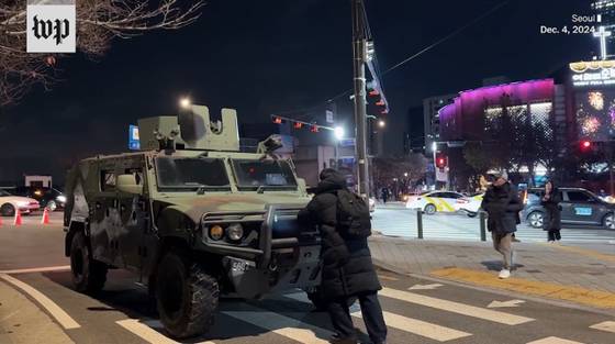 12.3 비상계엄 선포 다음날 새벽 한 시민이 비무장 상태의 소형전술차량을 막아서고 있다. 해당 차량은 장갑차로 잘 못 알려졌다. 사진 워싱턴포스트 웹사이트 캡처