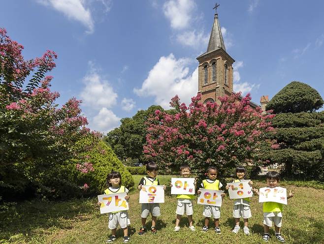 칠곡 가실성당에 활짝 핀 백일홍 앞에서 왜관읍 동산애 어린이집 원아들이 ‘가을아 안녕’이라는 손피켓을 들고 환하게 웃고 있다. /칠곡군 제공
