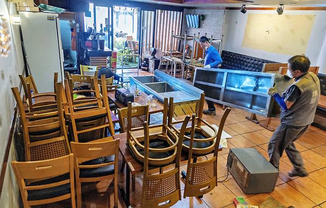 Pictured is a demolition worker carrying out a metal cabinet from the kitchen at a closed restaurant in Yongsan District, Seoul. As the number of self-employed business owners shutting down rise sharply year after year, demand for store demolitions has also increased, leading demolition-related companies to grow in scale. /Cho In-won