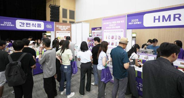 BGF리테일이 19일 서울 강남구 SC컨벤션센터에서 개최한 '2025 하반기 상품 컨벤션'에 참석한 편의점 CU 가맹점주들이 가정간편식(HMR) 등을 시식하며 상품기획자(MD)들의 설명을 듣고 있다. BGF리테일 제공
