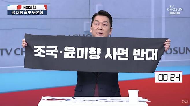 국민의힘 안철수 당 대표 후보가 19일 서울 중구 TV조선 스튜디오에서 진행된 텔레비전 토론회 마무리 발언에서 지난 15일 광복절 경축식에서 이재명 대통령을 향해 들어 보였던 ‘조국·윤미향 사면 반대’ 펼침막을 다시 선보이고 있다. TV조선 유튜브 채널 영상 캡처