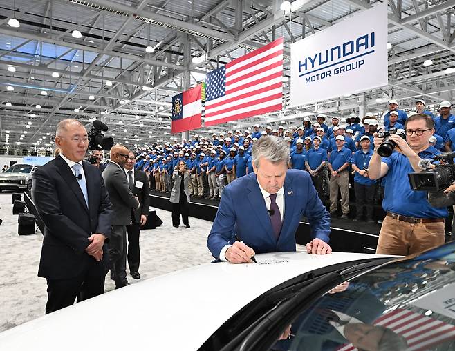 Hyundai Motor Group Executive Chairman Euisun Chung, left, looks on as Georgia Gov. Brian Kemp autographs a vehicle during a ceremony in Ellaville, the U.S. state of Georgia, on March 26, to open the South Korean carmaker's first dedicated EV factory, Hyundai Motor Group Metaplant America. [HYUNDAI MOTOR]