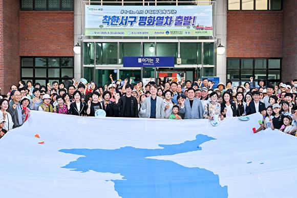 광주 서구가 추진하는 ‘착한서구 평화열차’ 첫 운행에 앞서 참가자 328명이 대형 한반도기를 잡고 기념촬영을 하고 있다.  [사진=광주시 서구]