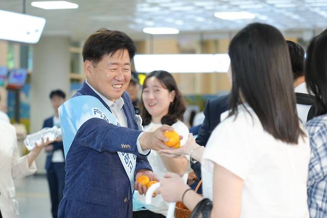 오영훈 지사가 지난 6월 21일 오후 제주국제공항 1층에서 열린 ‘가성비에 반하고, 가심비에 머무는 제주’를 주제로 한 관광객 환영행사에서 제주를 방문한 관광객에게 귤을 나눠주고 있다. (제주도청)
