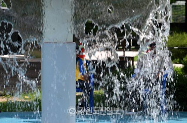 ▲ 18일 춘천 퇴계동 물놀이장 그늘에서 시민들이 시원한 물줄기를 바라보며 더위를 식히고 있다. 김정호 기자