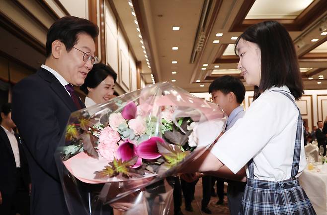 한일 정상회담을 위해 일본을 방문중인 이재명 대통령과 김혜경 여사가 23일 일본 도쿄의 한 호텔에서 열린 재일동포 오찬 간담회에서 꽃다발을 받고 있다./뉴시스