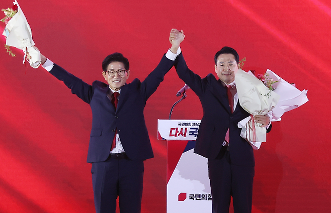 22일 충북 청주시 흥덕구 청주오스코에서 열린 국민의힘 제6차 전당대회에서 결선에 진출한 김문수, 장동혁 당대표 후보가 꽃다발을 받은 뒤 맞잡은 손을 들어 올리고 있다. 청주 연합뉴스