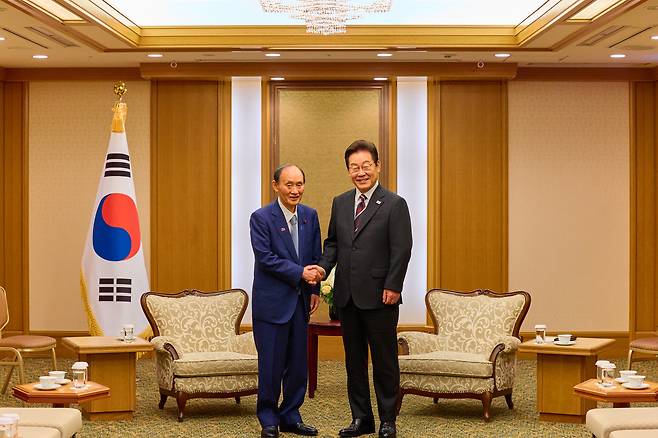 이재명 대통령이 24일 일본 도쿄의 한 호텔에서 일한의원연맹 회장인 스가 요시히데 전 일본 총리를 만나 인사하고 있다. /연합뉴스