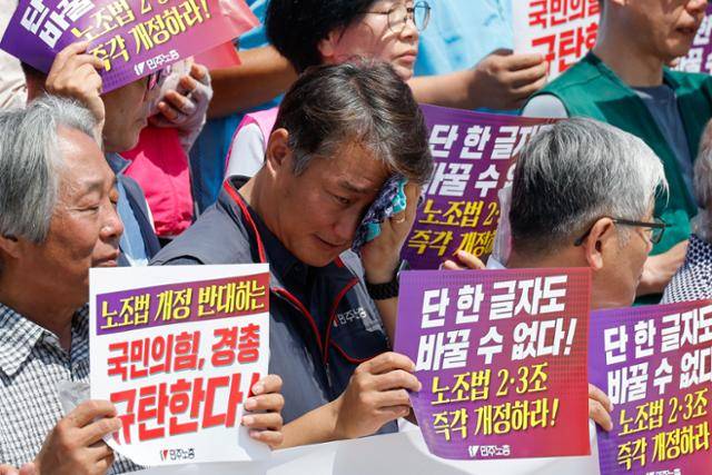 양경수 민주노총 위원장(가운데)이 22일 서울 여의도 국회 본청 계단에서 열린 '단 한 글자도 바꿀 수 없다! 노조법 2·3조 개정안 즉각 통과' 기자회견에서 땀을 닦고 있다. 뉴스1