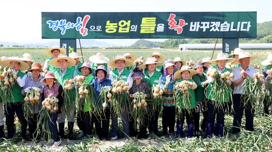 지난해 5월 23일 경북 문경시 영순면 공동영농단지에서 ‘경북 농업대전환 공동영농 성과 보고회’가 열린 가운데 참석자들이 농민들과 함께 수확한 양파를 들고 기념촬영하고 있다. 사진 경북도