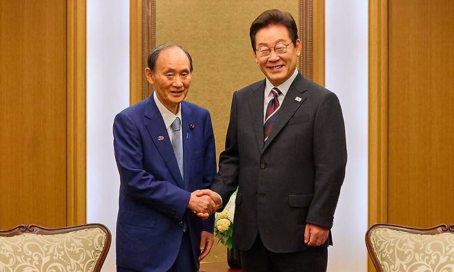 이재명 대통령이 24일 일본 도쿄의 한 호텔에서 일한의원연맹 회장인 스가 요시히데 전 일본 총리를 만나 인사하고 있다. 공동취재