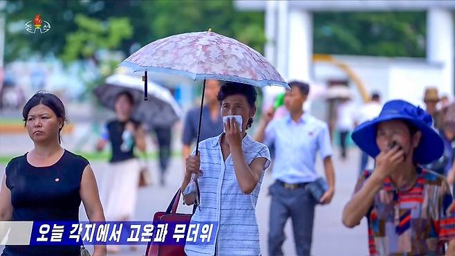 북한이 지난 8일부터 무더위 주의경보를 발령한 가운데 평양 시내에서 시민들이 양산을 쓰고 거리를 걸어가고 있다./조선중앙TV화면