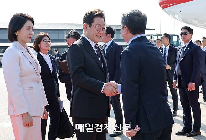 이재명 대통령과 김혜경 여사가 1박2일 방일 일정을 마치고 24일 오후 도쿄 하네다공항에서 미국 워싱턴으로 향하는 공군1호기에 올라 인사하고 있다.  김호영기자