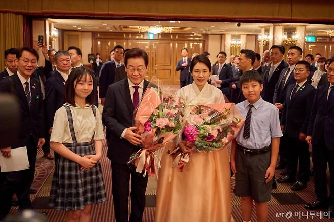 (서울=뉴스1) 이재명 기자 = 한일 정상회담을 위해 일본을 방문중인 이재명 대통령과 김혜경 여사가 23일(현지시간) 일본 도쿄의 한 호텔에서 열린 재일동포 오찬 간담회에서 화동들에게 꽃다발을 전달 받은 후 기념촬영을 하고 있다. (이재명 대통령 SNS. 재판매 및 DB금지) 2025.8.25/뉴스1  Copyright (C) 뉴스1. All rights reserved. 무단 전재 및 재배포,  AI학습 이용 금지.