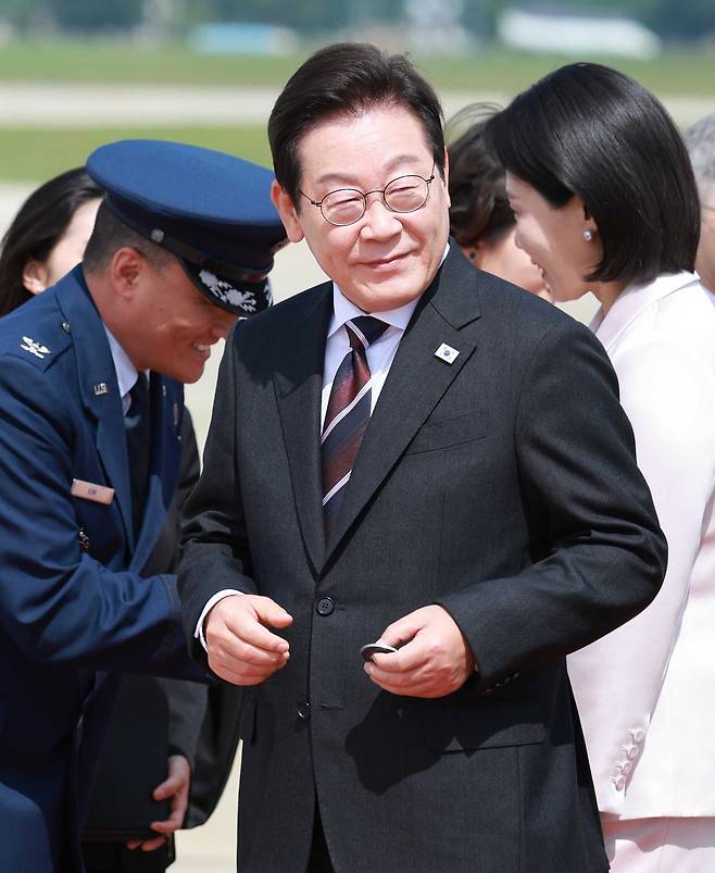 취임 후 처음 미국을 방문한 이재명 대통령이 24일(현지시간) 미국 워싱턴DC 인근 앤드루스 합동기지에 도착해 공군1호기에서 내려 영접 인사로 나온 미국 측 조슈아 킴 대령으로부터 기지 방문 기념 코인을 받아 들고 있다. [연합]