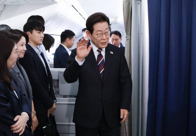 이재명 대통령이 24일(현지시간) 일본 도쿄 하네다공항 이륙 뒤 미국 워싱턴DC로 향하는 공군 1호기 기내에서 기자간담회 장소로 향하며 취재진을 향해 인사하고 있다. 연합뉴스