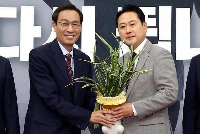 장동혁 국민의힘 대표(오른쪽)가 27일 오후 서울 여의도 국회에서 우상호 대통령비서실 정무수석에게 이재명 대통령 명의의 축하 난을 선물받고 기념촬영을 하고 있다. /뉴시스