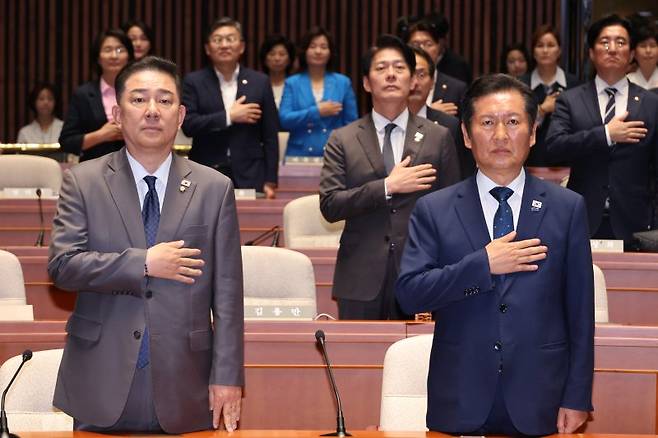 정청래 더불어민주당 대표(오른쪽)와 김병기 원내대표가 27일 국회에서 열린 의원총회에서 국기에 경례하고 있다. 연합뉴스