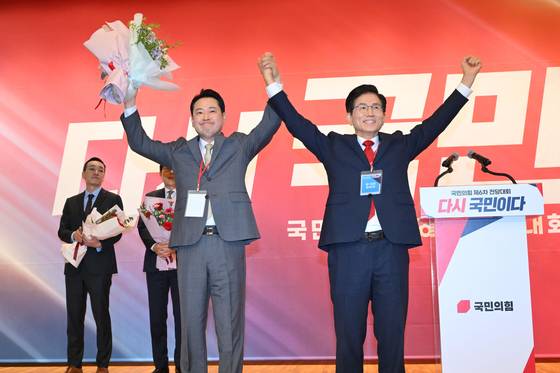 국민의힘 당 대표로 선출된 장동혁 후보와 탈락한 김문수 후보가 26일 국회 도서관에서 열린 전당대회 결선장에서 지지자들에게 인사하고 있다. 국회사진기자단