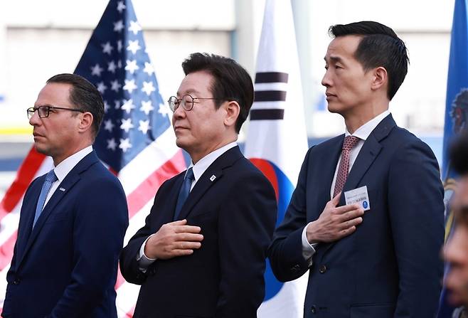 이재명 대통령이 26일(현지시간) 미국 필라델피아에 위치한 ‘한화 필리조선소’에서 열린 미국 해양청이 발주한 국가안보다목적선 ‘스테이트 오브 메인(State of Maine)’호의 명명식에서 국민의례를 하고 있다. 사진 왼쪽부터 조시 샤피로 펜실베니아 주지사, 이대통령, 김동관 한화그룹 부회장. [필라델피아 = 김호영 기자]