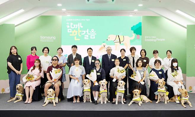 26일 경기도 용인 삼성화재 안내견학교에서 열린 32주년 기념식에서 신입 안내견들이 국민의힘 김예지 의원(앞줄 왼쪽)을 비롯한 새 파트너들과 함께 기념촬영을 하고 있다. 뒷줄 왼쪽 다섯 번째부터 박태진 삼성화재 안내견 학교장, 이문화 삼성화재 사장, 이수성 장애인 먼저 실천 운동본부 이사장, 김소현 해마루 반려동물 의료 재단 이사장. 삼성화재 제공
