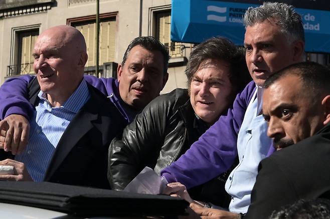 아르헨티나 대통령 하비에르 밀레이 아르헨티나 대통령(오른쪽에서 세 번째)이 27일(현지시간) 로마스데사모라에서 총선 유세 카퍼레이드를 하던 도중 군중이 자신에게 물건을 던지자 반응하고 있다. AFP연합뉴스