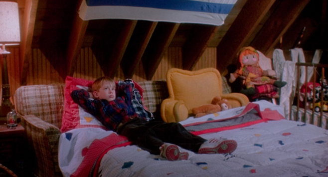 영화 ‘나 홀로 집에’(1990)의 한 장면. 신발을 신은 채로 침대 위에 당당히 누운 케빈을 보면, 도둑 일당을 잠시나마 응원하게 된다. 정신을 다잡고 간신히 버텨보지만… [사진 출처=20세기 폭스]