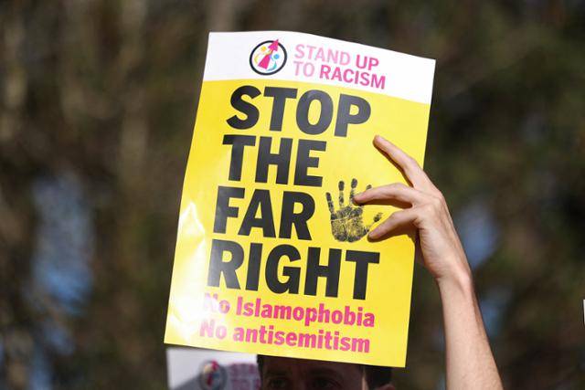 지난 8일 영국 위럴에서 열린 이민 지지 시위에서 한 참가자가 미국 극우 세력의 'STOP THE STEAL(훔치지 말라)'을 패러디한 'STOP THE FAR RIGHT(극우를 멈춰라)' 문구를 들고 있다. 위럴=로이터 연합뉴스