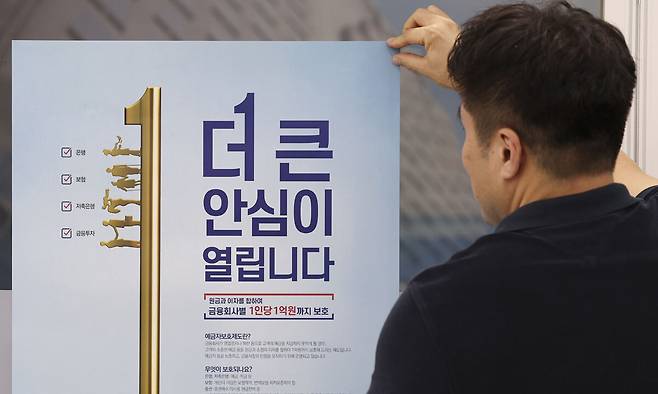 지난 21일 서울 중구 예금보험공사에서 직원이 예금자 보호 한도 1억원 상향 시행 안내문을 붙이고 있다. 뉴시스