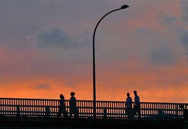 석양이 붉게 물든 하늘 아래로 걸어가는 가족들의 모습이 평화롭게 보인다