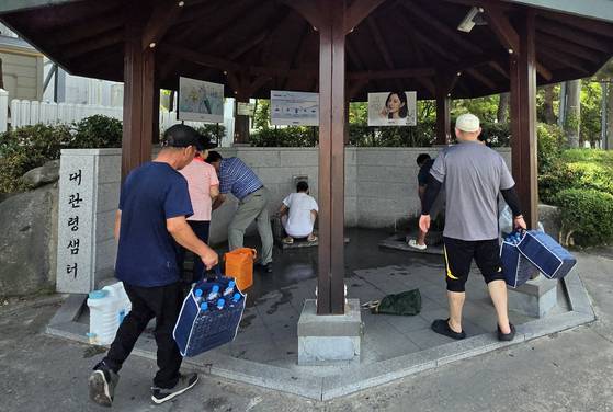 31일 강원도 강릉시 대관령샘터에서 시민들이 식수로 사용할 물을 받고 있다. [연합뉴스]