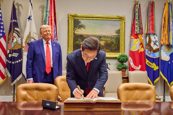이재명 대통령이 25일(현지시간) 미국 워싱턴 DC 백악관에서 도널드 트럼프 미국 대통령이 지켜보는 가운데 방명록을 작성하고 있다. 연합뉴스&nbsp;