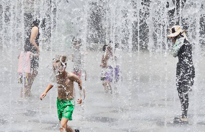 시민들이 바닥 분수에서 나오는 물줄기를 맞으며 더위를 식히고 있다./뉴스1