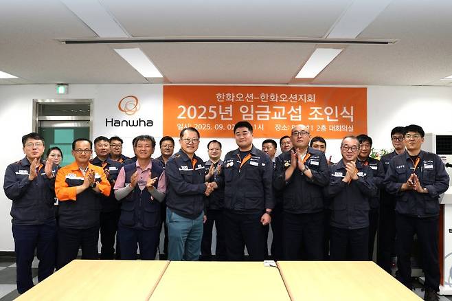 한화오션 김희철 대표이사(앞줄 왼쪽 네번째)와 전국금속노조 경남지부 한화오션지회 김유철 지회장(앞줄 왼쪽 다섯번째) 등 노사 교섭위원들이 2일 임금 교섭 조인식을 마친 후 기념촬영을 하고 있다. 한화오션 제공