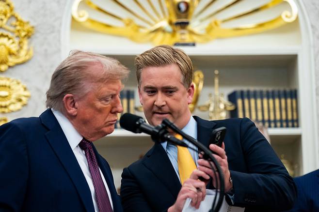 도널드 트럼프 미국 대통령(왼쪽)이 2일 백악관에서 폭스뉴스의 피터 두시 기자가 보여주는 자신과 관련된 밈 영상을 보고 있다. /AP 연합뉴스