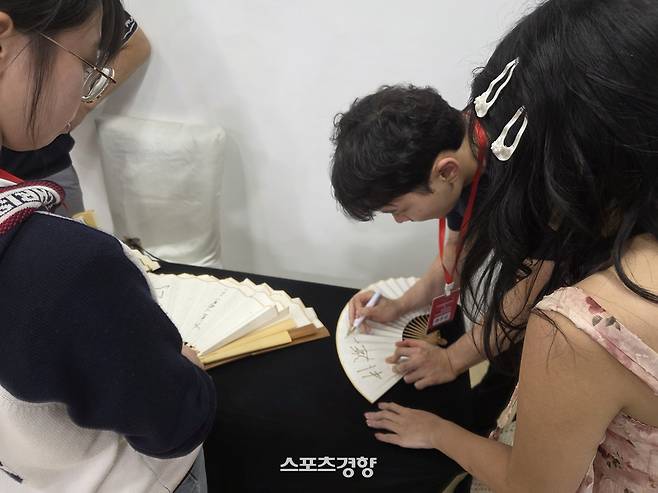 박정환 9단이 3일 자신을 찾아온 팬들이 가져온 부채에 사인을 해주고 있다.    칭다오 | 윤은용 기자