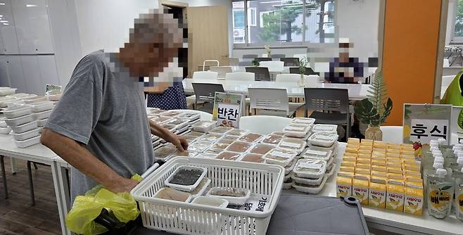 ▲ 우만사회복지관에서 이용자가 밥과 국, 반찬 등을 담고 있다.