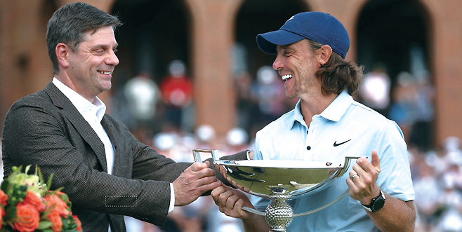 브라이언 롤랩(왼쪽) PGA투어 CEO가8월 24일 미국 조지아주 애틀랜타이스트 레이크 골프클럽에서 열린 PGA투어플레이오프 최종전 투어 챔피언십에서164번째 출전 대회에서 첫 우승을 차지한토미 플리트우드(잉글랜드)에게우승컵을 전달하고 있다. /사진 AFP연합