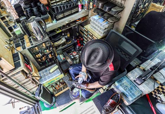 A cobbler surnamed Jo polishes a customer’s shoes in central Seoul on Sept. 1. [KANG JUNG-HYUN]