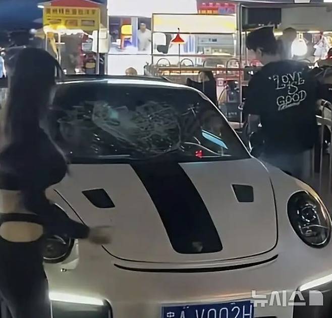 [뉴시스] 중국 구이양 시내에서 여성이 흰색 포르쉐 차량 유리를 박살 낸 모습.(사진=왕이신문)