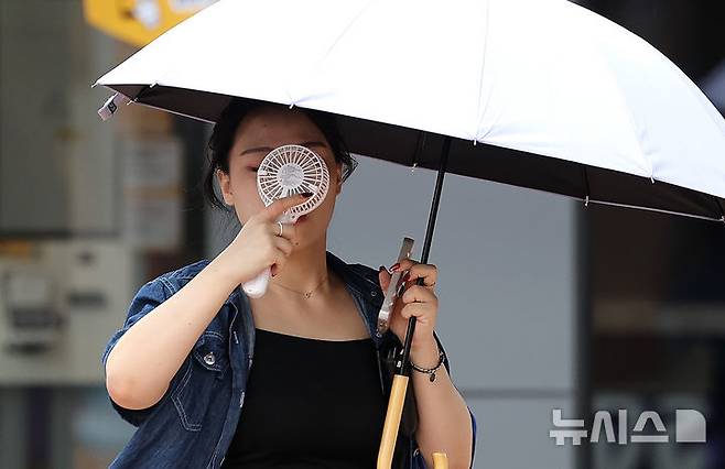 [대구=뉴시스] 이무열 기자 = 폭염이 연일 계속된 23일 대구 중구 동성로에서 한 시민이 우산과 손 선풍기를 들고 길을 걷고 있다. 2025.07.23. lmy@newsis.com