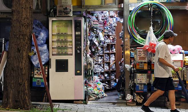 늦은 밤 불을 밝힌 문구점 앞에 빛바랜 커피 자판기가 자리를 지키고 있다. 작동을 멈춘 지 5년이 넘었다. 첨단 기능과 새로운 상품을 갖춘 자판기들이 등장하고 있지만 이 낡은 자판기도 기능을 하고 있다. 속이 빈 채 창고 역할을 한다. 앞으로도 한동안은 자판기인 척할 것이다.